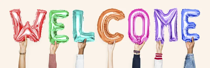 Multiple hands hold up different colored balloon letters that say WELCOME