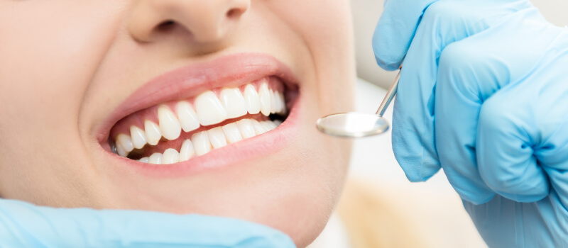 Closeup of a woman smiling at the dentist during her routine cleaning and checkup in Alvin, TX