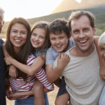 A smiling multigenerational family of a grandpa, grandma, parents, and 2 young children