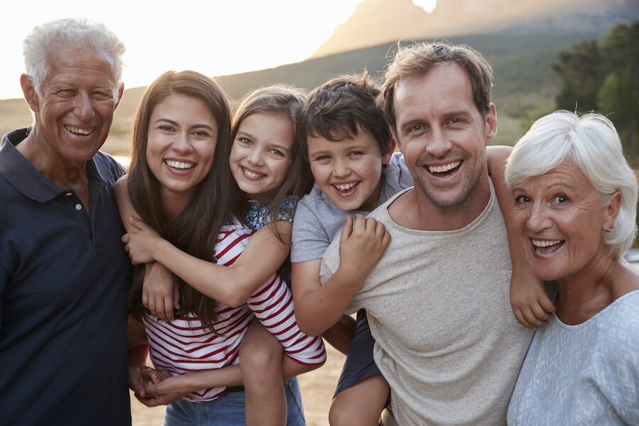 A smiling multigenerational family of a grandpa, grandma, parents, and 2 young children